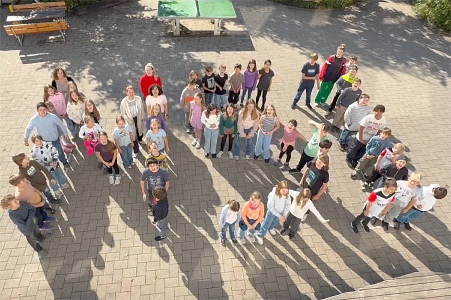 MSI – Team Demokratie: Eine Gruppe von Schülern und Schülerinnen steht auf dem Pausenhof und bildet die Buchstaben „MSI“